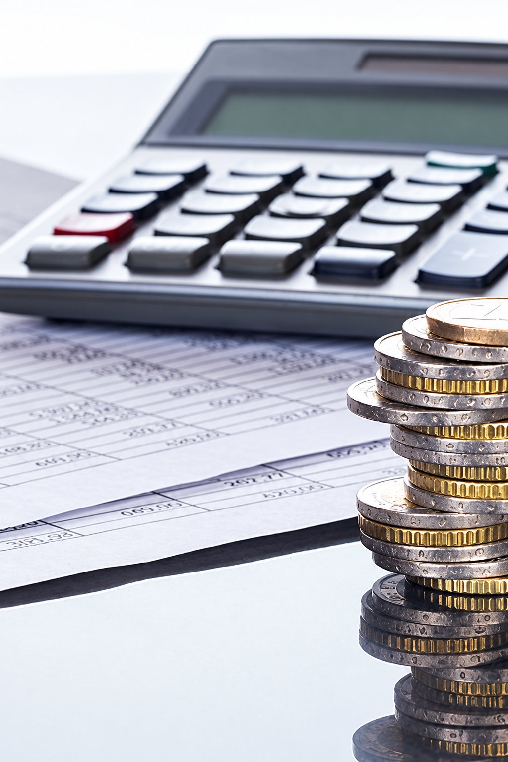 Pile de pièces d’euro devant une calculatrice et des documents comptables